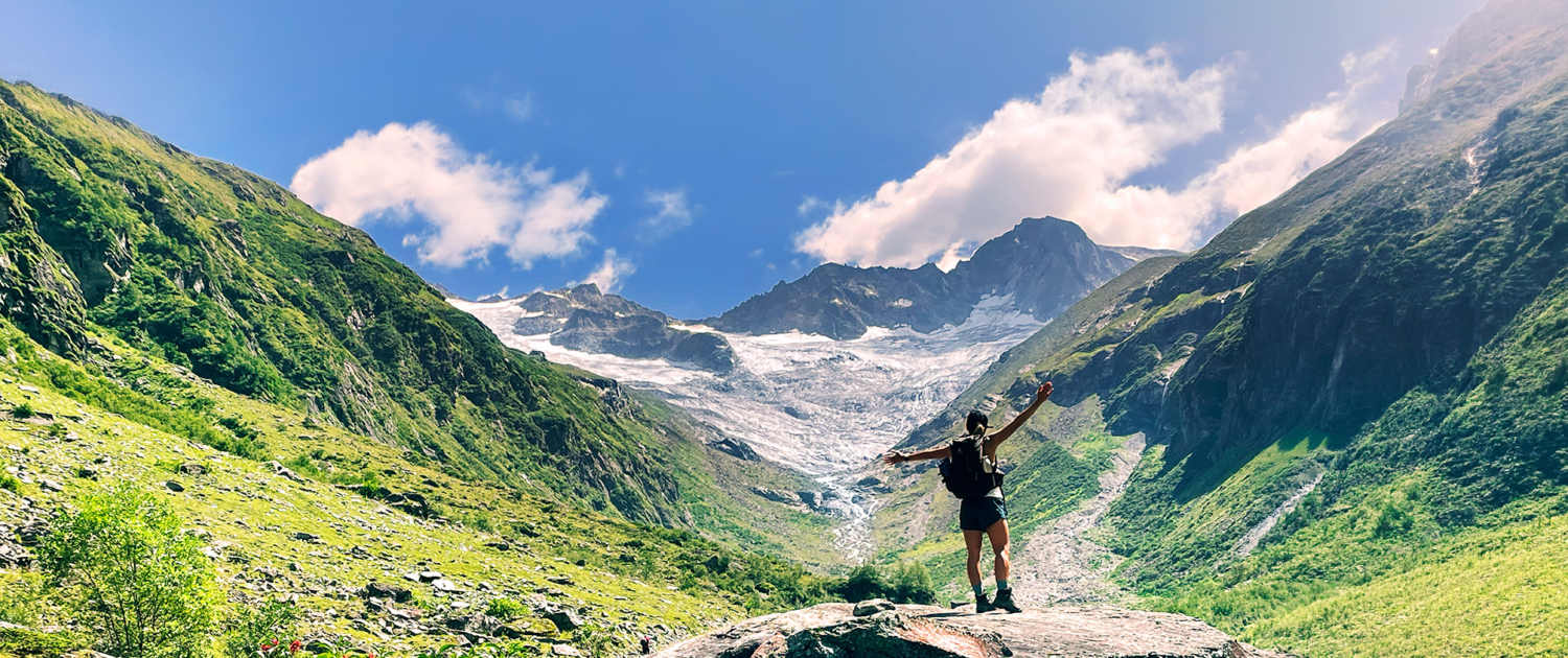 Über die Chakrenlehre Eine junge Frau steht auf einem Felsen in einem Alpen Hochtal und öffnet sich der schöpferischen Energie